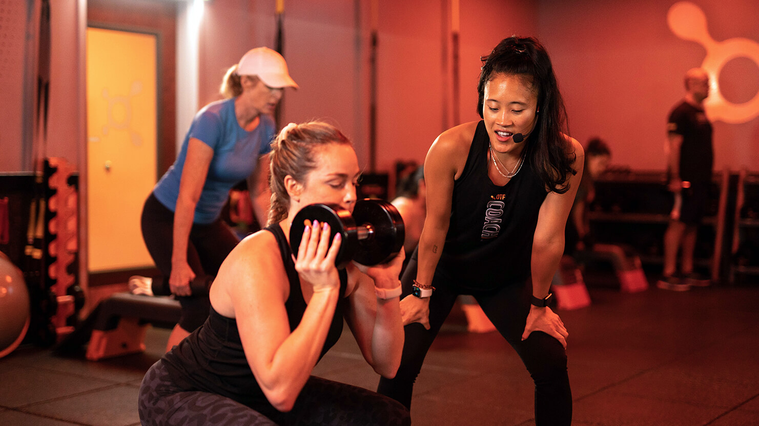A coach supports a client at Orange Theory during a workout